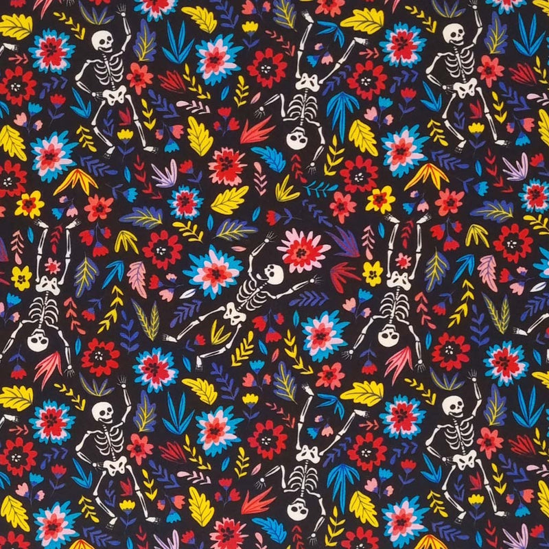 Skeletons and bright flowers are printed on a black cotton poplin fabric by Rose & Hubble
