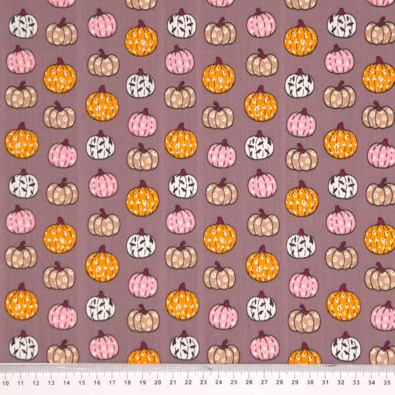 Ditsy decorated pumpkins printed on a grey polycotton fabric with a cm ruler