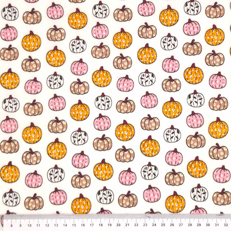 Ditsy pumpkins printed on a white polycotton fabric with a cm ruler