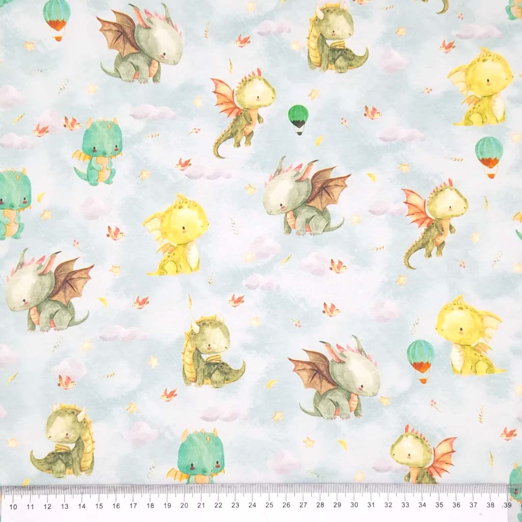 Cute dragons are printed on a pale blue cotton jersey fabric with a cm ruler