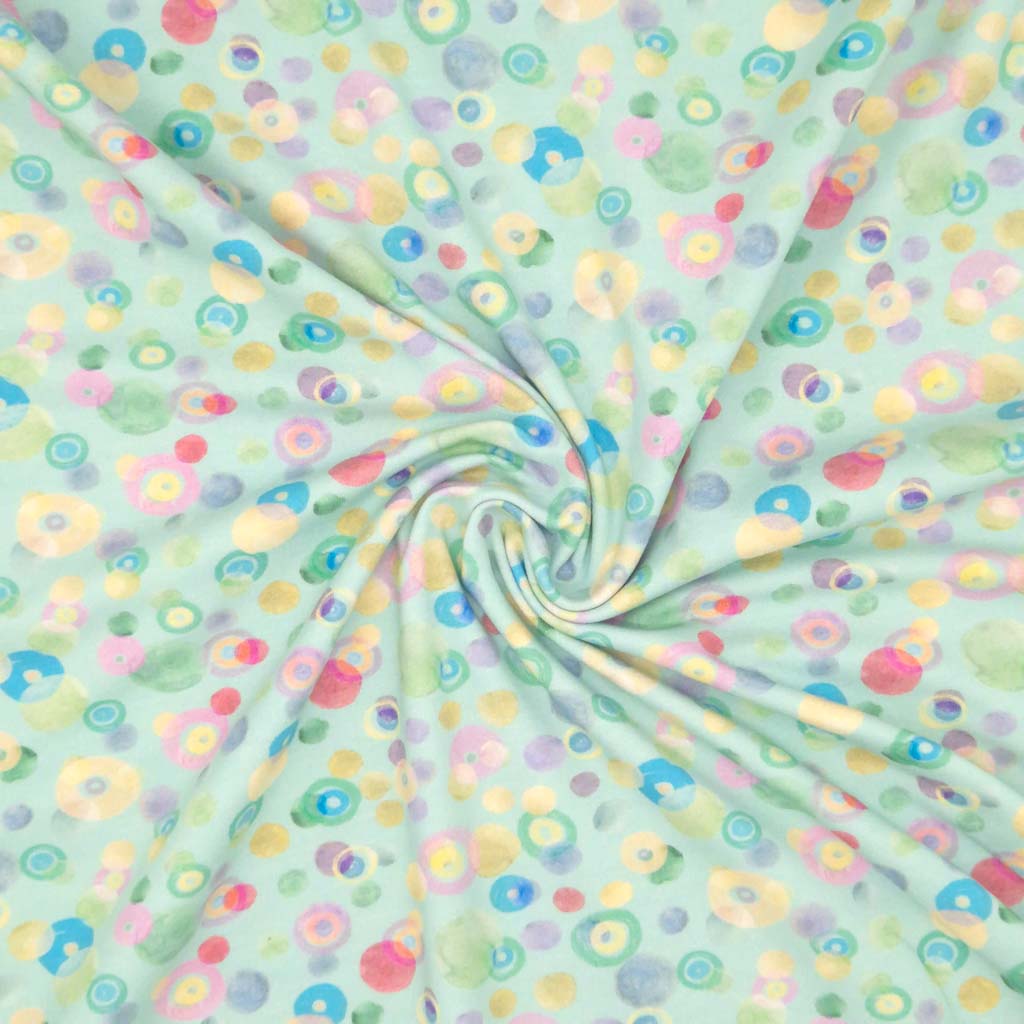 Pastel coloured spots printed on an aqua cotton jersey fabric