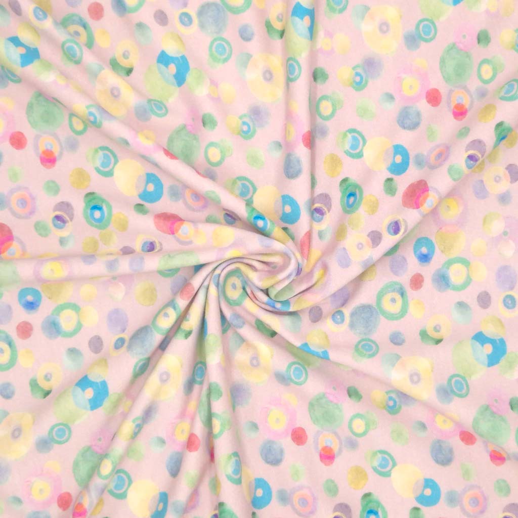 Pastel coloured spots printed on a pale pink cotton jersey fabric