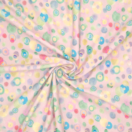 Pastel coloured spots printed on a pale pink cotton jersey fabric