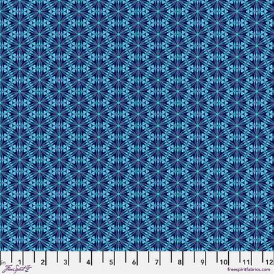 A geometric pattern in bright blues printed on a cotton quilting fabric with a cm ruler