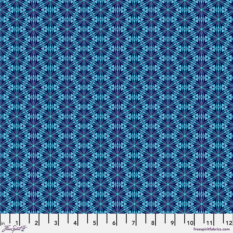 A geometric pattern in bright blues printed on a cotton quilting fabric with a cm ruler