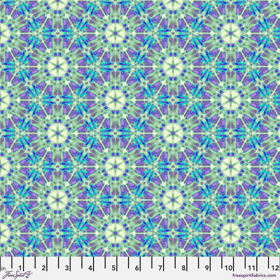A geometric pattern in purples and greens printed on a cotton quilting fabric with a cm ruler