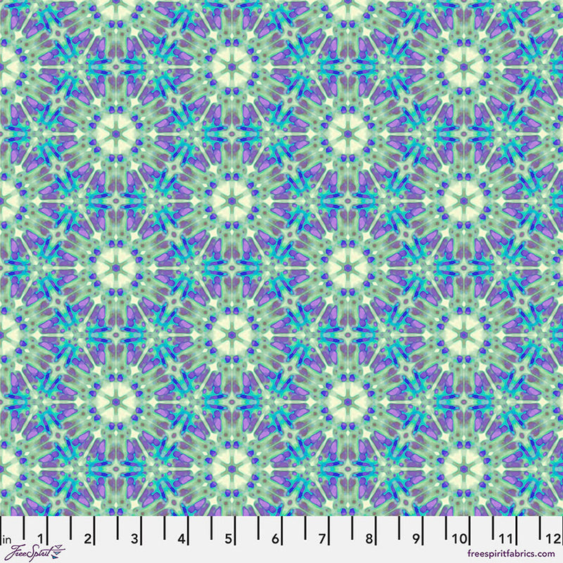 A geometric pattern in purples and greens printed on a cotton quilting fabric with a cm ruler