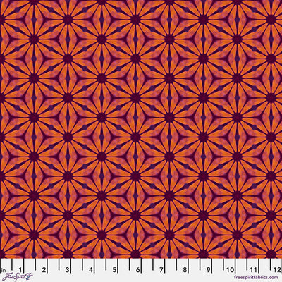 A floral geometric pattern in reds and oranges printed on a cotton quilting fabric with a cm ruler