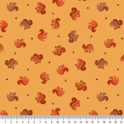 Pattern of red and brown squirrels on a yellow cotton quilting fabric  with a ruler at the bottom.