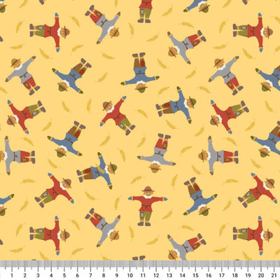 Pattern of scarecrows on a yellow cotton quilting fabric with a ruler at the bottom.