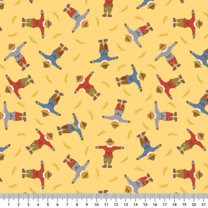 Pattern of scarecrows on a yellow cotton quilting fabric with a ruler at the bottom.