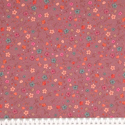 A ditsy floral pattern printed on a dusky pink cotton jersey fabric with a cm ruler