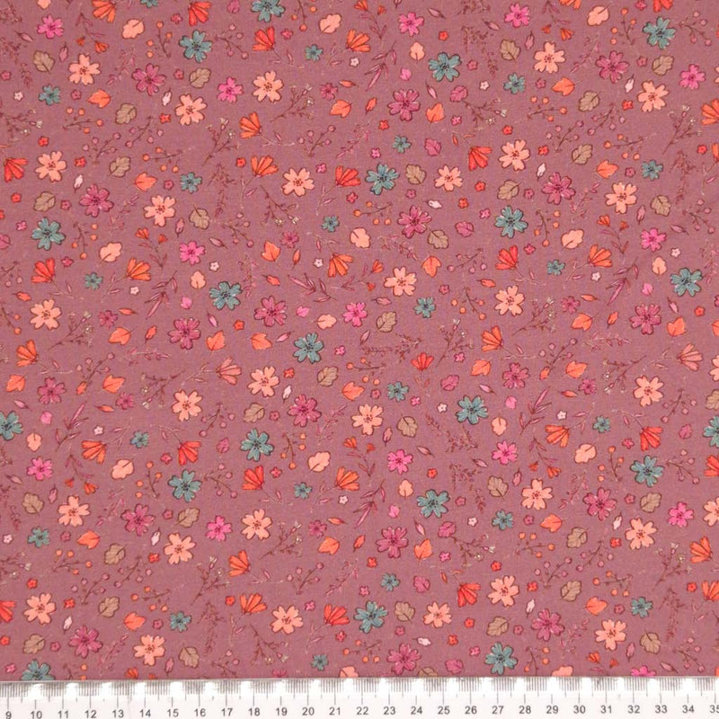 A ditsy floral pattern printed on a dusky pink cotton jersey fabric with a cm ruler