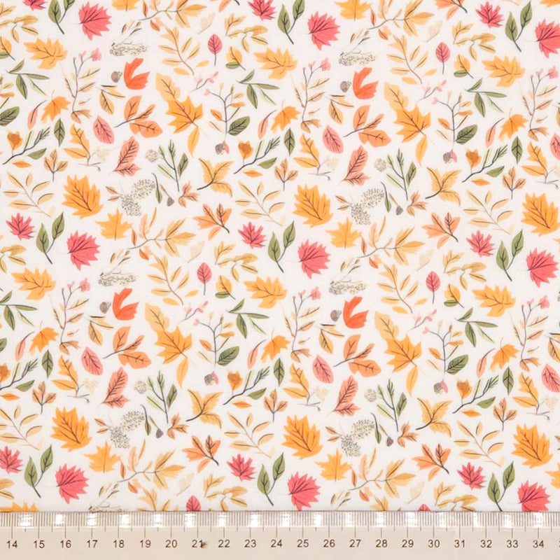 Pattern of autumn leaves and branches on a white polycotton fabric with a cm ruler