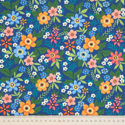 Colorful floral pattern on a blue polycotton fabric with a cm ruler