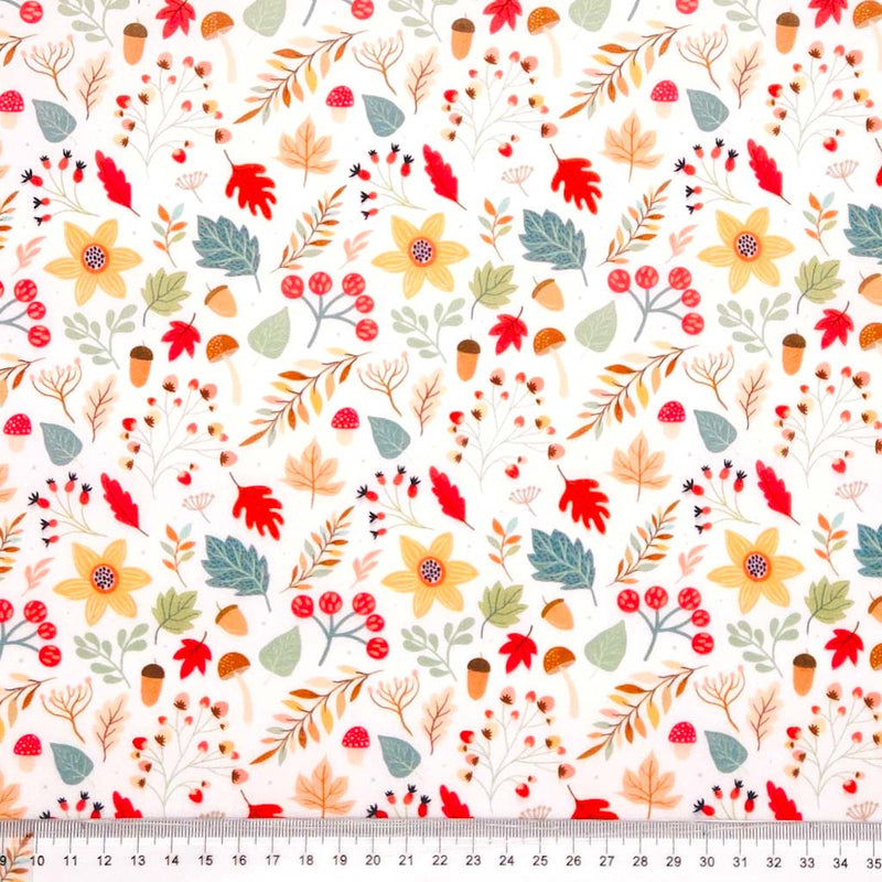 Pattern of autumn leaves, flowers, and berries on a white polycotton fabric with a cm ruler