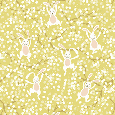 Bouncing Easter bunnies jumping in the spring blossom printed on a yellow cotton fabric