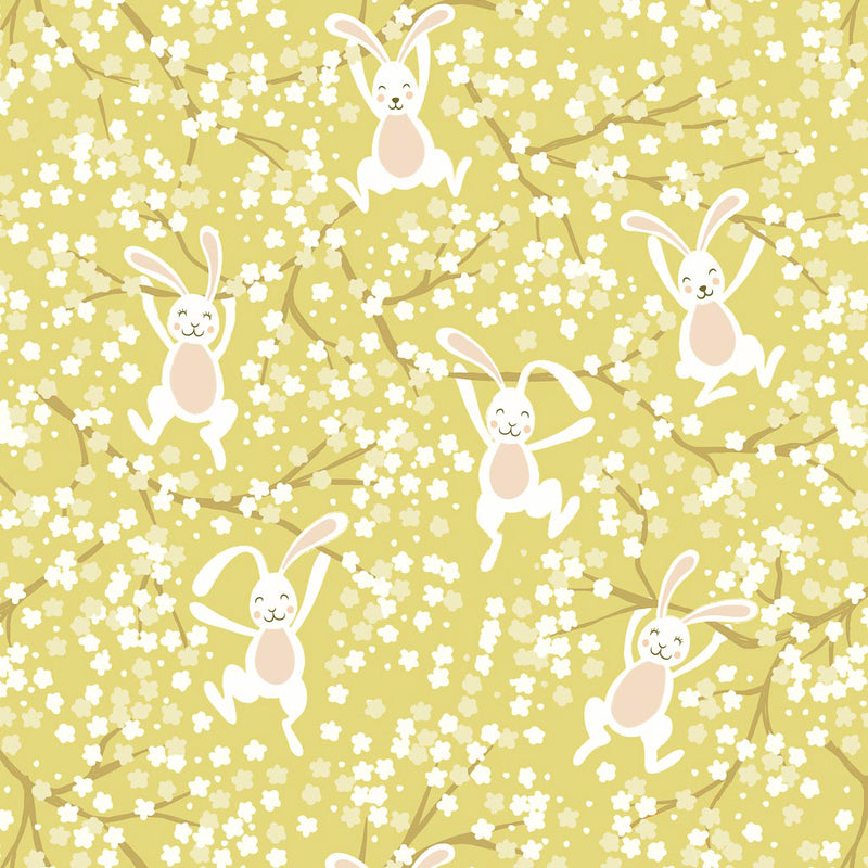 Bouncing Easter bunnies jumping in the spring blossom printed on a yellow cotton fabric