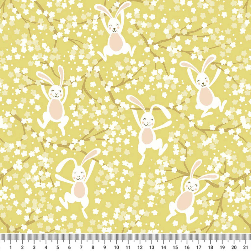 Bouncing Easter bunnies jumping in the spring blossom printed on a yellow cotton fabric with a cm ruler