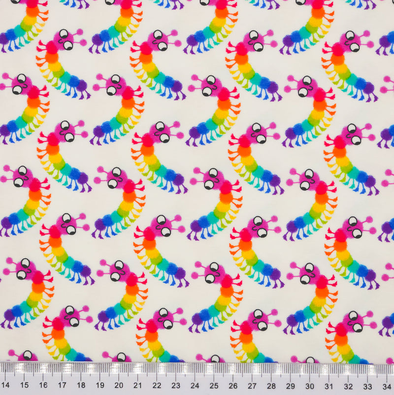 Brightly coloured caterpillars printed on an ivory cotton jersey fabric with a cm ruler