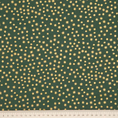 Green fabric with gold star pattern and a ruler at the bottom for scale.
