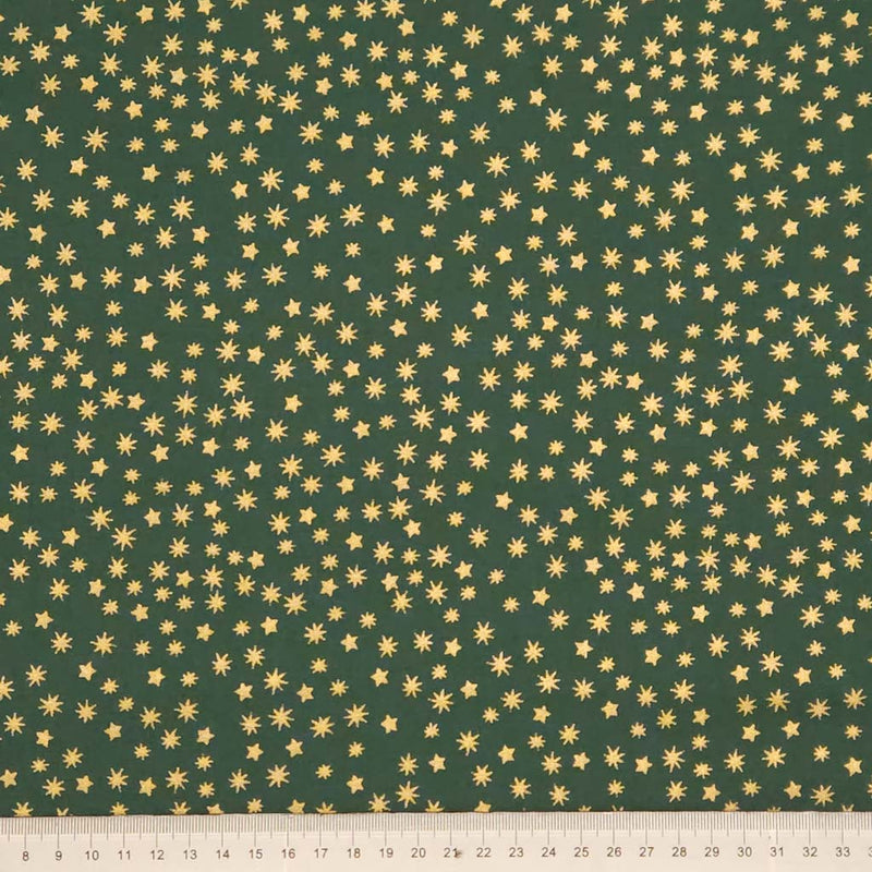 Green fabric with gold star pattern and a ruler at the bottom for scale.