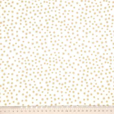 Pattern of small gold stars on a cream cotton fabric with a ruler at the bottom.