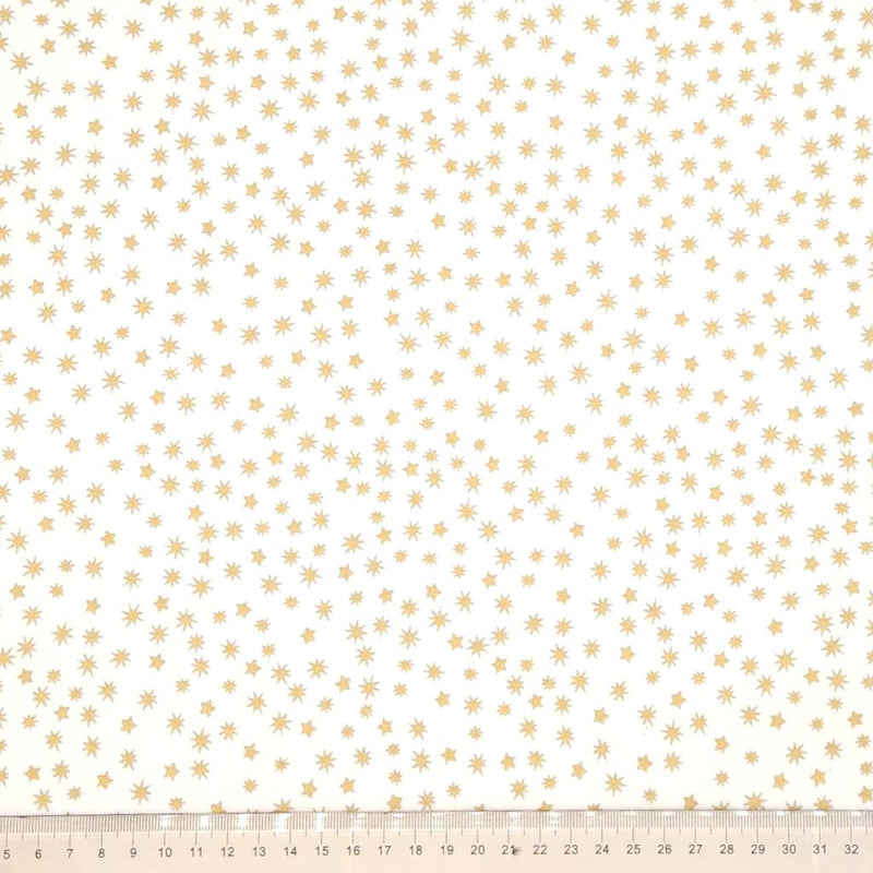 Pattern of small gold stars on a cream cotton fabric with a ruler at the bottom.