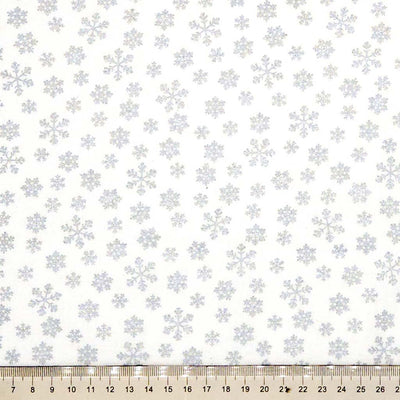 Pattern of snowflakes on a white cotton fabric with a ruler at the bottom.