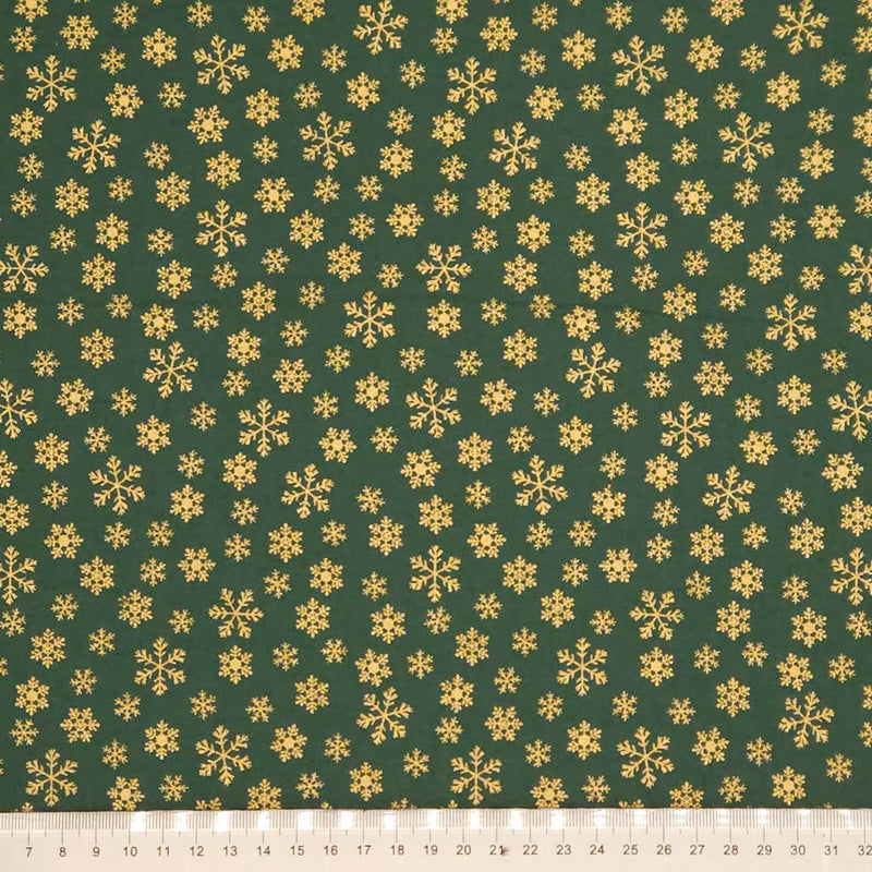 Pattern of gold snowflakes on a green cotton fabric with a ruler at the bottom.