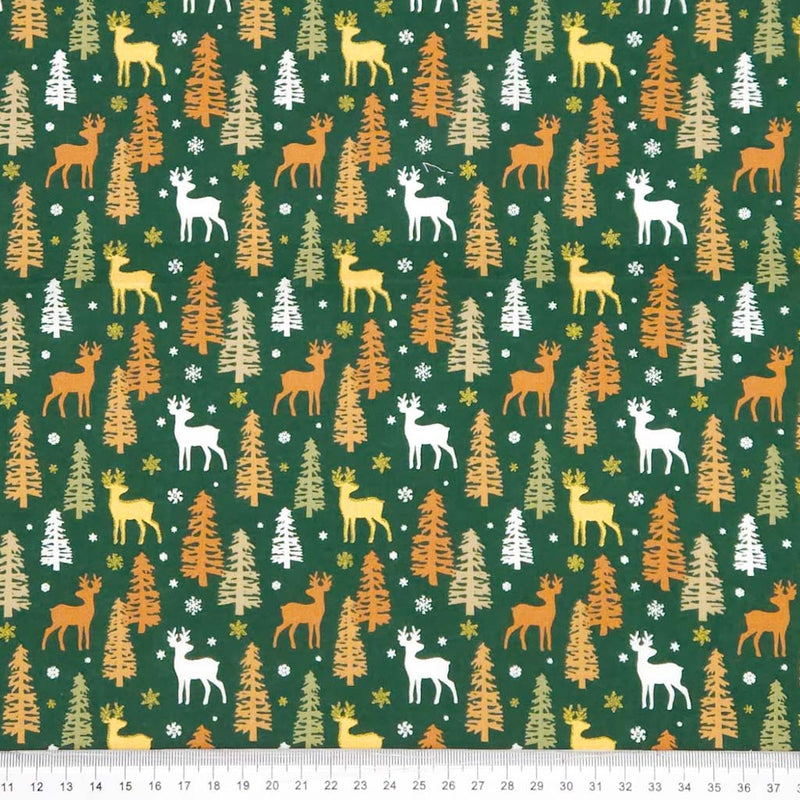 Pattern of deer and trees on a green christmas cotton fabric with measurement scale at the bottom.