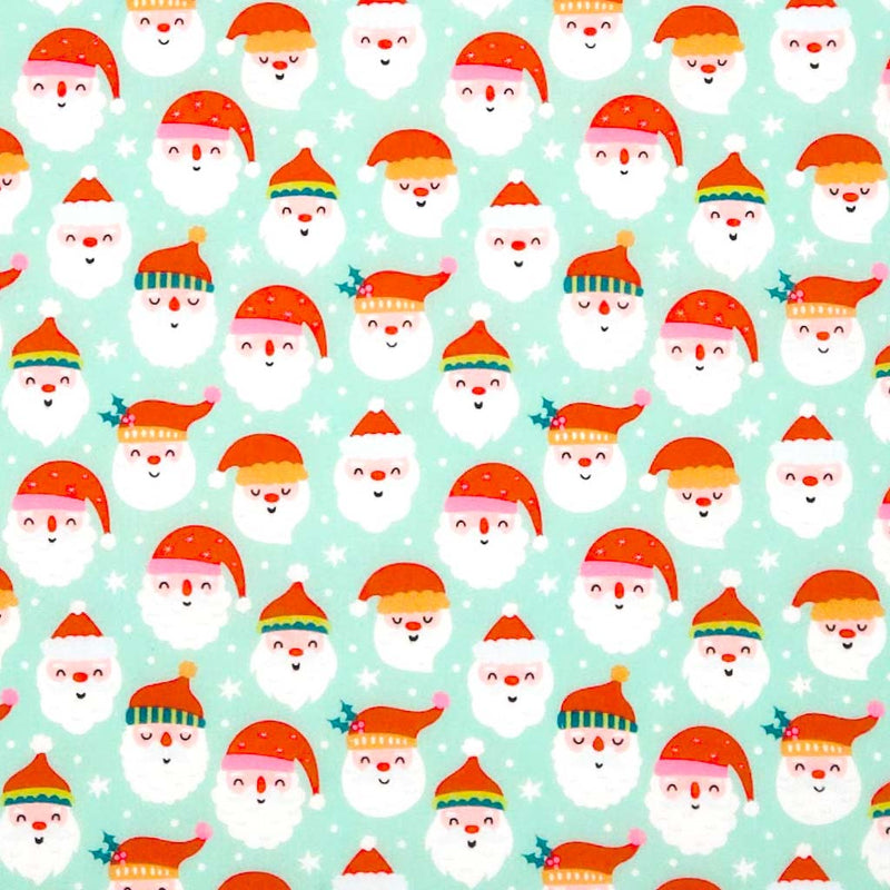 Pattern of cartoon Santa Claus faces with colorful hats on a light blue polycotton fabric