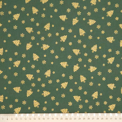 Green fabric with gold Christmas tree and snowflake pattern, ruler at the bottom for scale.