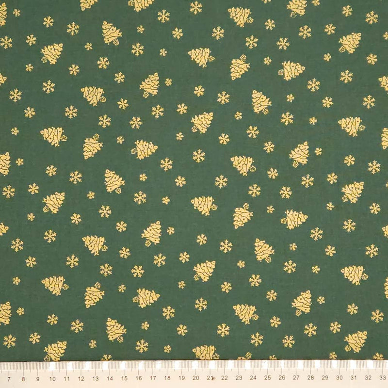 Green fabric with gold Christmas tree and snowflake pattern, ruler at the bottom for scale.