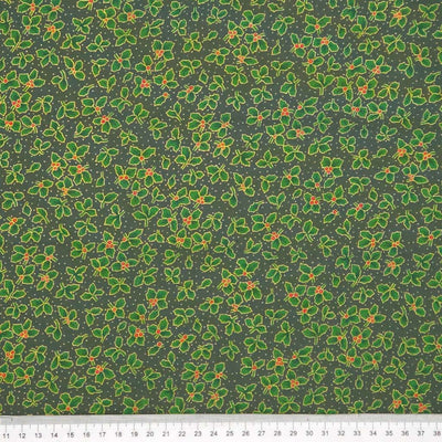 Pattern of green holly leaves and berries on a dark green christmas fabric with a cm ruler
