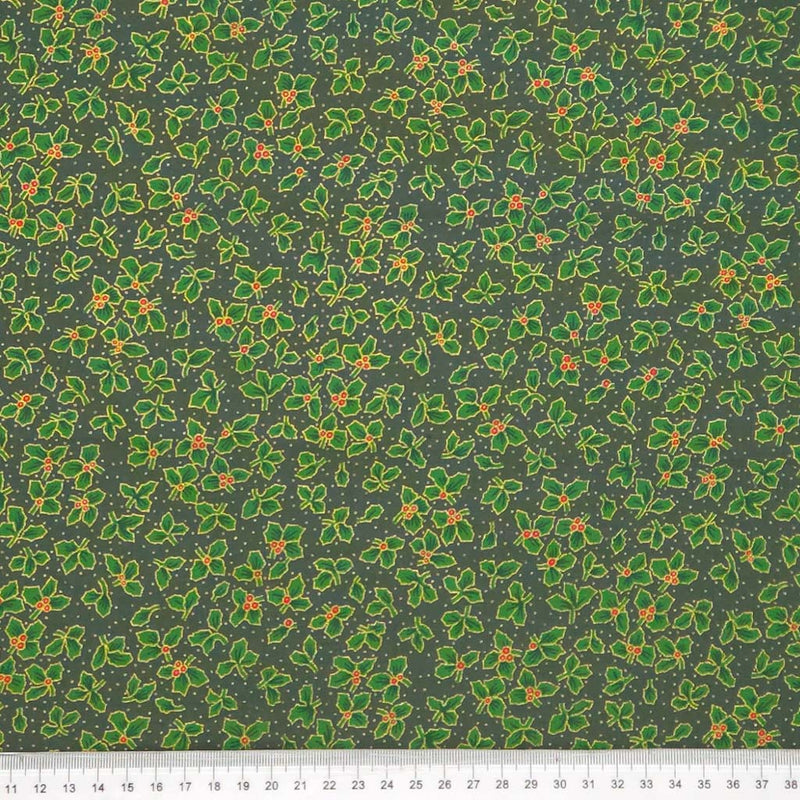 Pattern of green holly leaves and berries on a dark green christmas fabric with a cm ruler