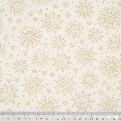 A stunningly intricate gold lacquered snowflake design printed on a cream 100% cotton fabric with a cm ruler