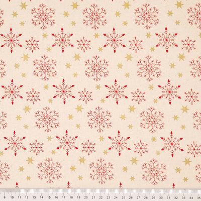 Red scandi snowflakes and gold metallic stars printed on a natural 100% cotton fabric. with a cm ruler