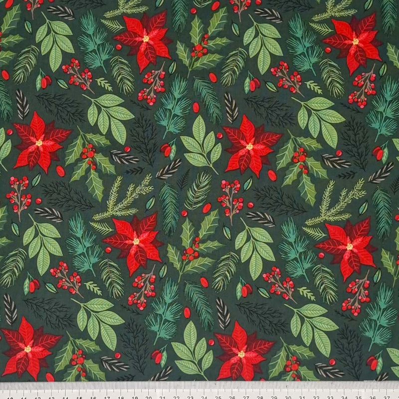 Poinsettia and mixed Christmas leaves such as fern, holly and berries are printed on a bottle green, 100% cotton fabric by Rose & Hubble with a cm ruler