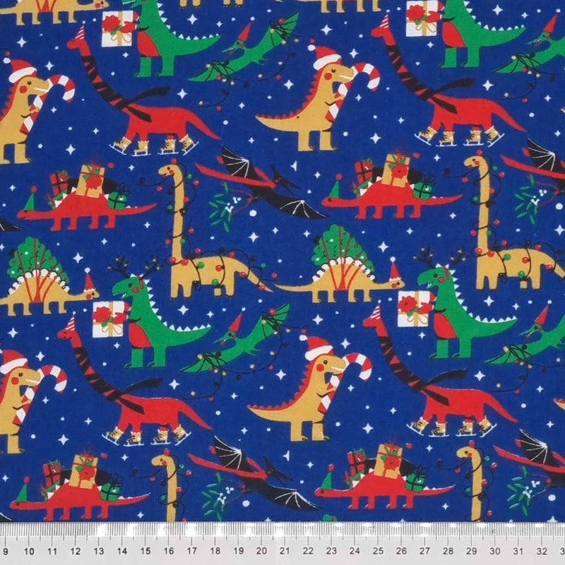 Dinosaurs wrapped in fairy lights are printed on a blue christmas polycotton fabric with a cm ruler