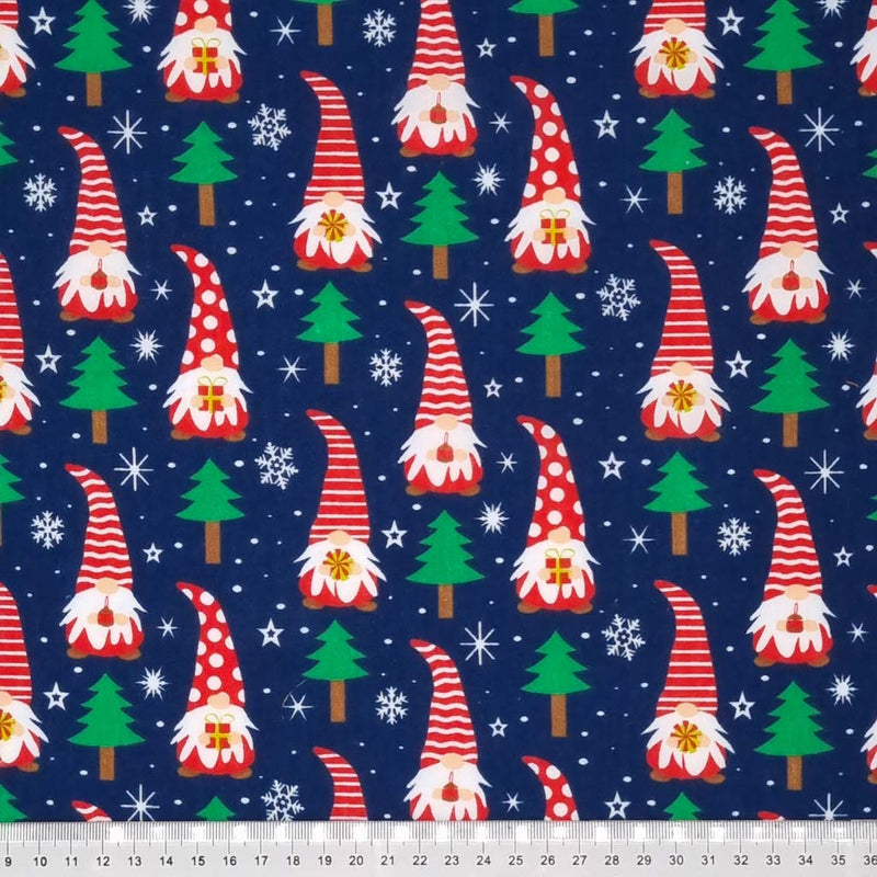 Christmas gonks with red hats and surrounded by snowflakes are printed on a navy polycotton fabric with a cm ruler