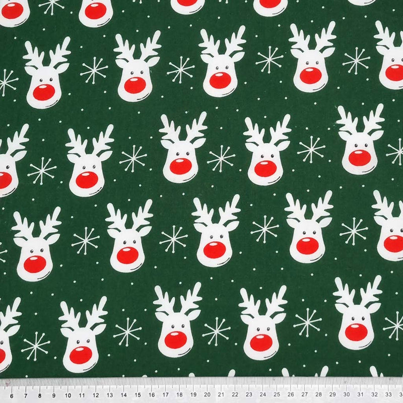 Smiling reindeer faces printed on a green polycotton fabric with a cm ruler