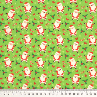 Santa and candy canes printed on a green polycotton fabric with a cm ruler