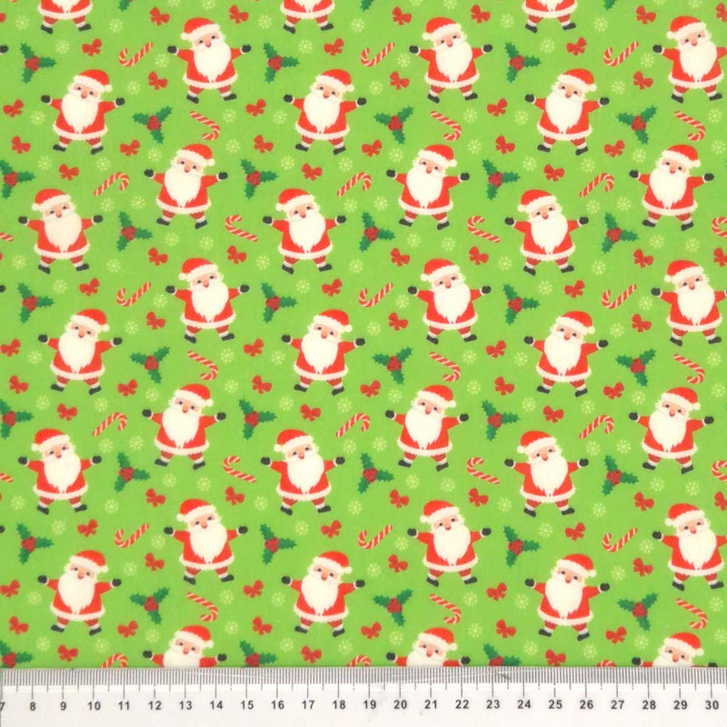 Santa and candy canes printed on a green polycotton fabric with a cm ruler