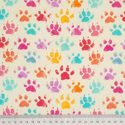 Colourful paw prints printed on a light beige cotton fabric with a cm ruler