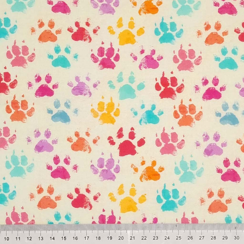 Colourful paw prints printed on a light beige cotton fabric with a cm ruler