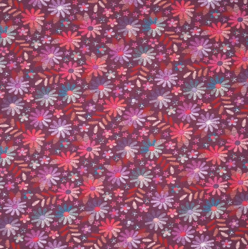 A mulberry coloured single cotton jersey fabric printed with embroidery look flowers