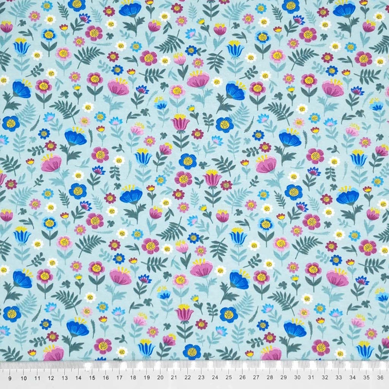 Ditsy flowers are printed on a sky blue cotton jersey fabric with a cm ruler