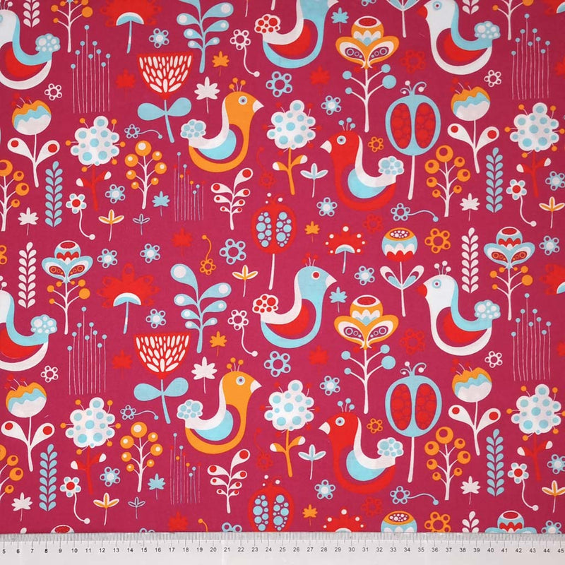 Blue scandinavian style birds are printed on a cerise pink cotton fabric with a cm ruler