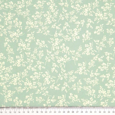 A cream vine floral printed on a sge green cotton poplin fabric by Rose & Hubble with a cm ruler